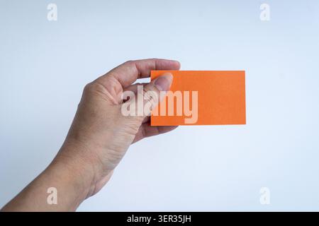 Hand holding an orange blank card, isolated on white background. Stock Photo