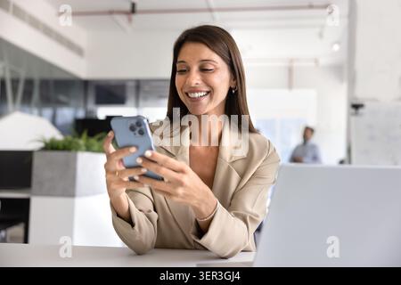 Positive Latina businesswoman, office manager using her smartphone Stock Photo