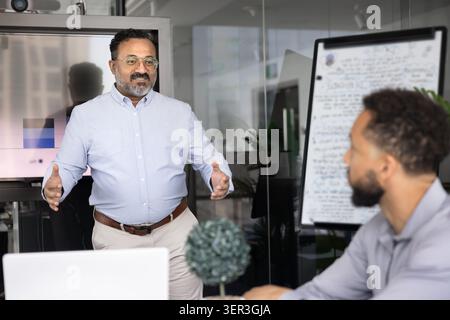 Mature Indian businessman speaking during corporate meeting Stock Photo