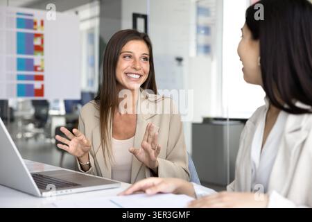 Two women colleagues having friendly conversation at workplace Stock Photo