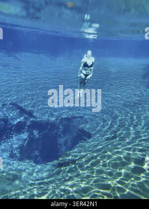 Woman diving to hot spring with clear blue water, underwater shot, Kikuletwa Chemka Hot Springs, Rundugai, Kilimanjaro region, Tanzania Stock Photo