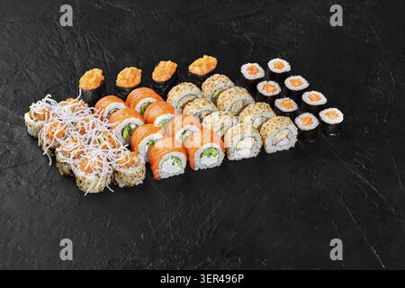 Different types of sushi rolls arranged on a black background, creating an appetizing display for japanese cuisine lovers Stock Photo