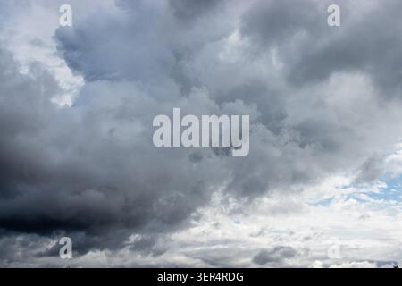 A powerful, turbulent sky filled with dramatic dark grey storm clouds and lighter white formations, hinting at an approaching weather change or impend Stock Photo