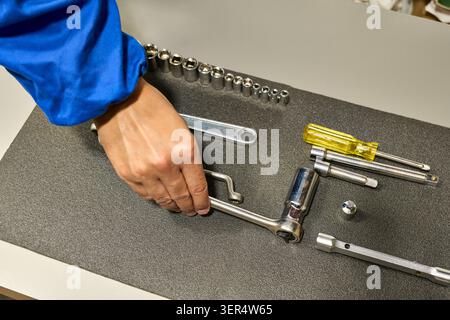 High-angle shot of an unrecognizable repairman's hands  grabbing a tool from his tool Stock Photo