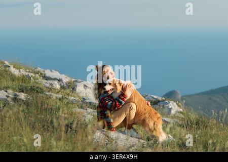 A woman hugs her Border Collie in mountain scenery with soft natural light. Emotional atmosphere creates peaceful adventure feeling. Stock Photo