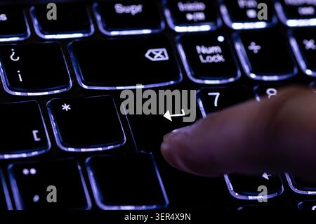 Close-up of finger presses the input key on the blue keyboard. Selected focus. Stock Photo
