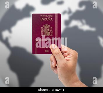 Close-up of hand of man holding Spanish passport over map background. Stock Photo