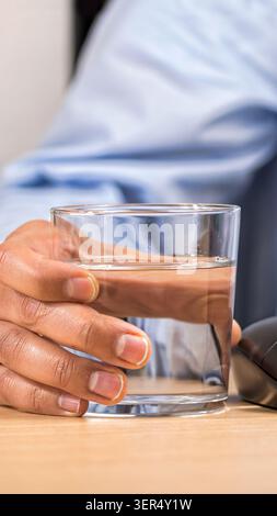 Close-up of hand of a businessman in the office drinking a glass of mineral water Stock Photo