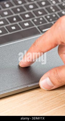 Hand of a businessman working on the laptop and using the touchpad on the wooden table in the office Stock Photo
