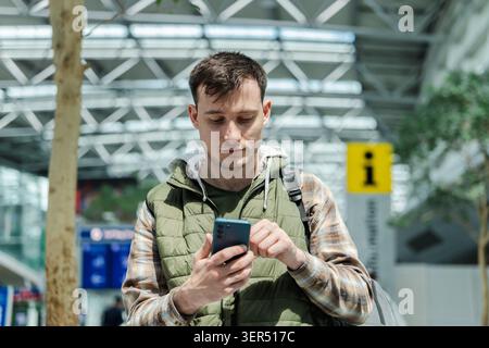 Young traveler using smartphone in airport terminal while waiting for departure Stock Photo