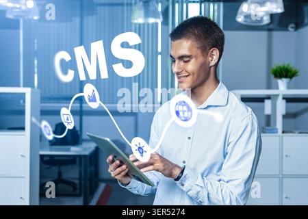 Young man using a tablet in an office setting for content management system tasks Stock Photo