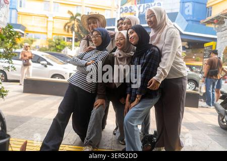 Jakarta , Indonesia - June 1st, 2026 - A group of female friends wearing hijab taking a selfie in the street. Stock Photo