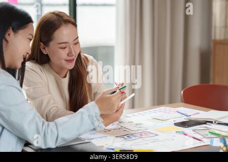 Asian female UX designers collaborating on mobile application interface design in office Stock Photo