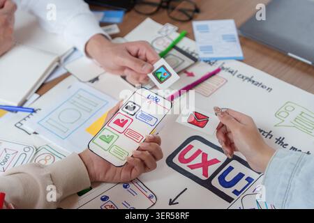 UX UI designers prototyping mobile app interface with paper wireframes Stock Photo