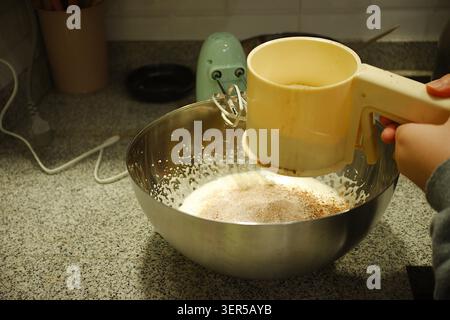 The flour is being sifted to produce fine flour for making traditional family cakes. Stock Photo