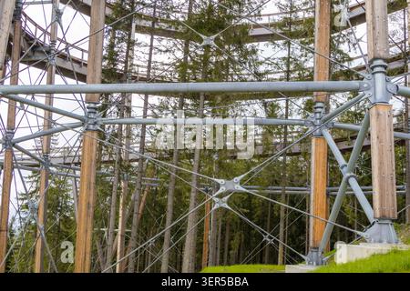 Steel framework of elevated mountain observation tower surrounded by forest landscape. Modern engineering structure, tourism infrastructure Stock Photo