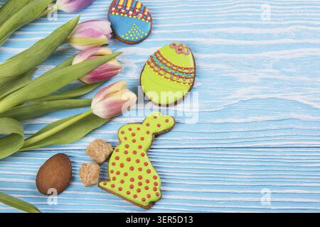 Composition of tulips and gingerbread cookies on white and blue wooden background for Happy Easter Stock Photo