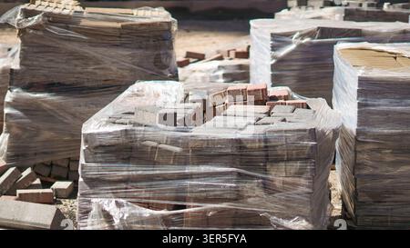 Paving stones wrapped in plastic on pallets at construction site. Stock Photo