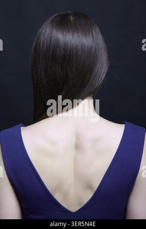 Young brunette woman in blue dress. Female view from the back side Stock Photo