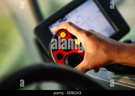 Close up of farmer's hand operating modern agricultural machinery with advanced joystick Stock Photo
