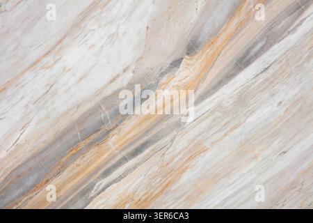 Natural stone surface showing veins and patterns in shades of white, gray, and brown with textures revealing layers and colors. Stock Photo