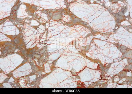 A surface of natural stone with various patterns. The stone features a light background with dark and orange veins. It appears smooth and polished. Stock Photo