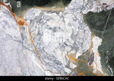 A piece of marble stone with various colors and patterns. The marble has shades of white, gray, and orange with clear lines and textures. Stock Photo