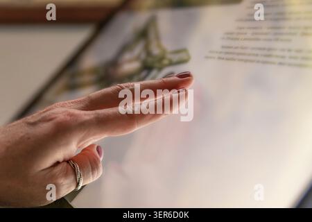 Woman using interactive touchscreen information display in modern museum exhibition hall indoors Stock Photo