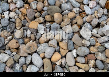 Close-up of smooth, rounded pebbles in various earthy tones including gray, brown, and beige, highlighting natural stone textures Stock Photo