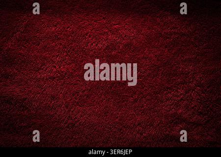 Dark red textured terry cloth background with a dramatic vignette effect. Stock Photo