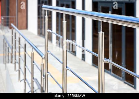 Polished stainless steel railing features sleek, reflective surfaces and modern design. Minimalist architectural safety hardware provides durable supp Stock Photo