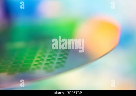 Electronic wafer showing a patterned surface with colorful blurred background Stock Photo