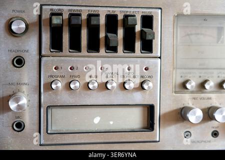 Detailed close-up view of vintage silver hi-fi audio cassette deck control panel featuring retro mechanical push buttons, metallic volume knobs, Stock Photo
