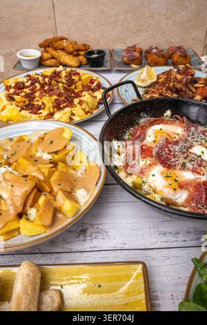 Broken eggs with Serrano ham and fried green peppers, all cooked together in the pan and then served on a flat plate, very traditional Stock Photo