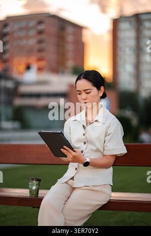 Young woman concentrating on digital tablet in city park Stock Photo