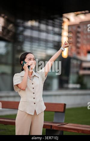 Young adult woman talking on smartphone with excited gesture Stock Photo