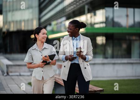 Diverse businesswomen walking and collaborating outdoors in city Stock Photo
