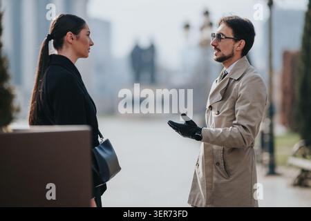 Business conversation between two professionals standing face to face in an urban outdoor setting Stock Photo