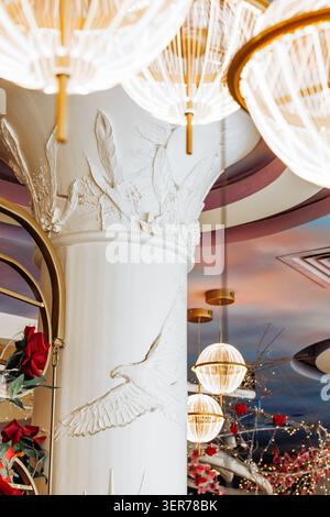 Stunning low-angle view of an elegant white architectural column featuring intricate bas-relief carvings of flying birds, leaves and flowers Stock Photo