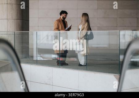 Business colleagues having a professional discussion with documents near a glass railing in a modern building Stock Photo