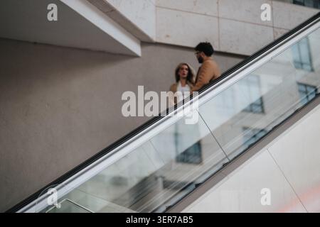 Business colleagues talking on an indoor glass escalator in a modern office building lobby Stock Photo