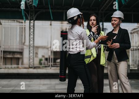 Women engineers in safety gear discussing a construction site project during a professional meeting Stock Photo