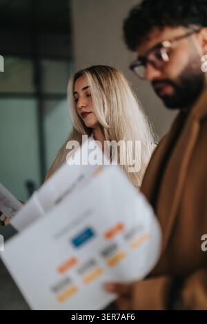 Two business colleagues reviewing printed charts and documents together in a modern office Stock Photo