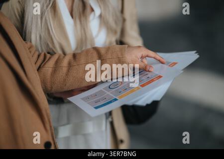Business colleagues reviewing printed documents and charts during a casual office discussion Stock Photo