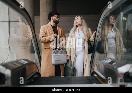 Business colleagues on escalator carrying luggage and talking while heading through modern transit hub Stock Photo