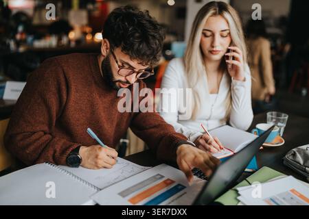 Two young professionals working on business planning in a cafe with laptop and notes Stock Photo