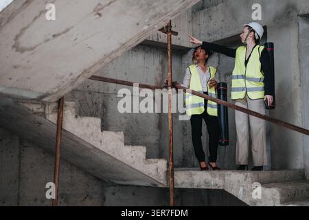 Two female engineers inspecting a concrete construction site while wearing safety vests and hard hat Stock Photo