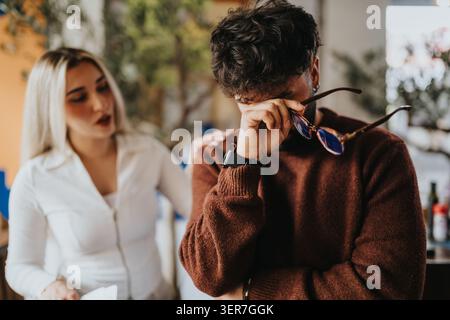 Business partners in tense conversation as one man rubs his eyes while a colleague speaks Stock Photo