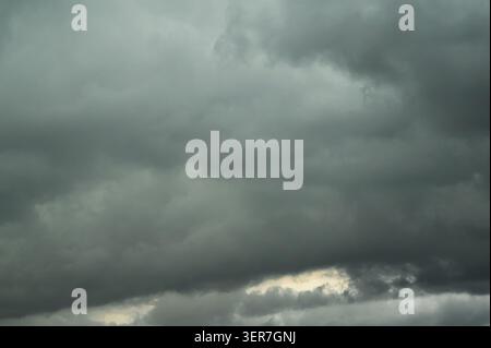 Dark storm clouds fill the entire sky with a bright break below. Stock Photo