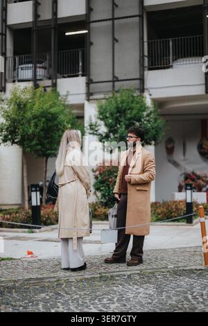 Business colleagues talking outdoors in coats during an urban sidewalk meeting on a cool day Stock Photo